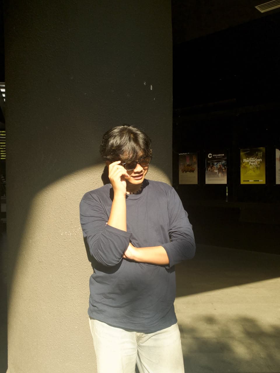 Alif Reezi, standing outdoors in sunlight, taking a phone call.